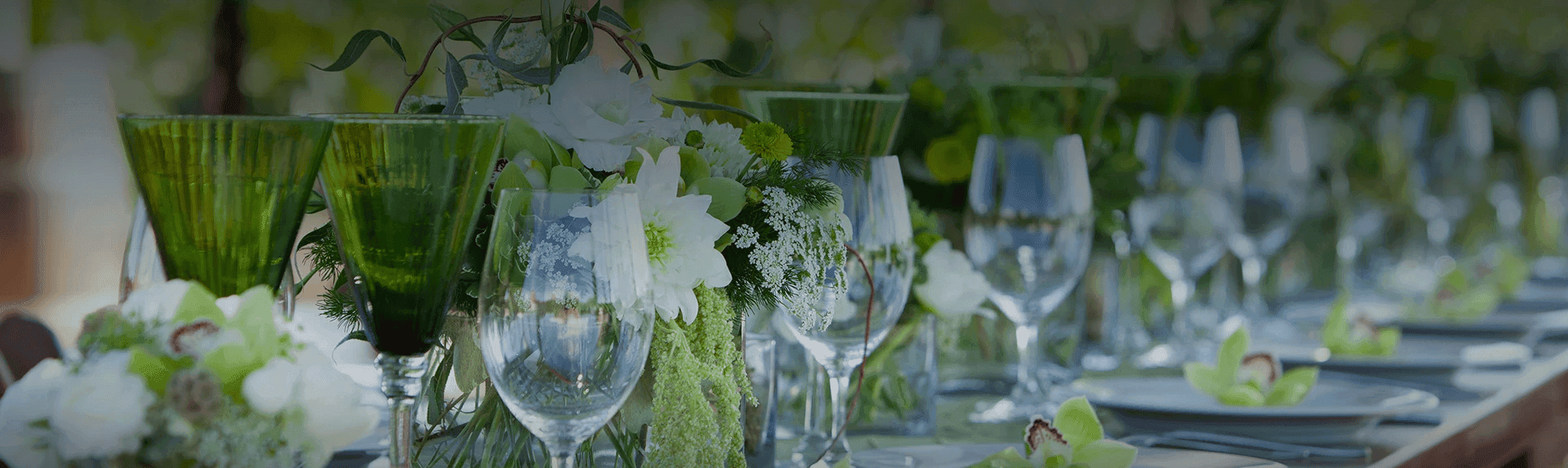 A beautifully arranged dining table adorned with green glassware and floral centerpieces.